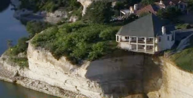 House dangling as cliff crumbles